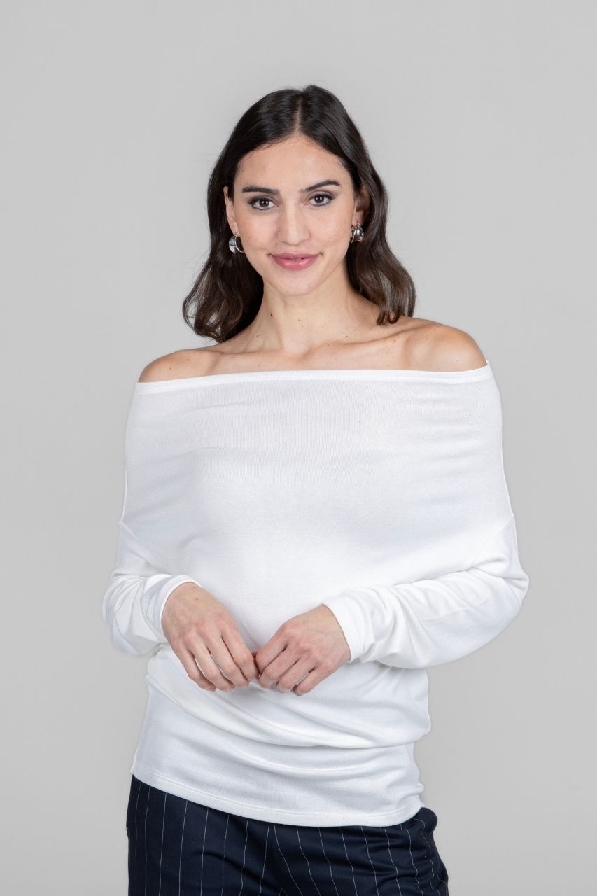 Woman wearing a white off-shoulder sweater against a gray background