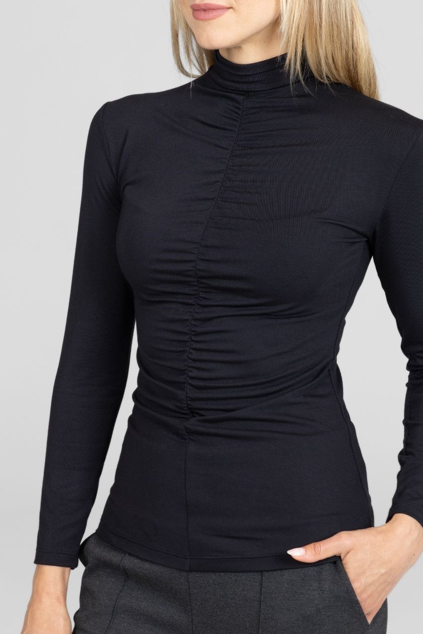 Close up view of black long-sleeve mock neck top worn by a woman on a gray background