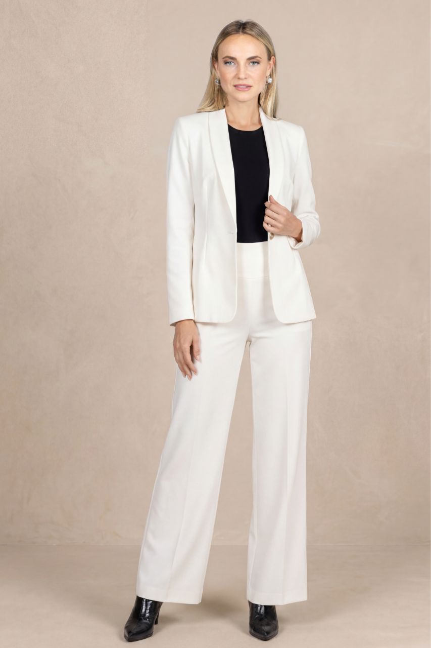 Woman wearing a white suit with a black top on a beige background