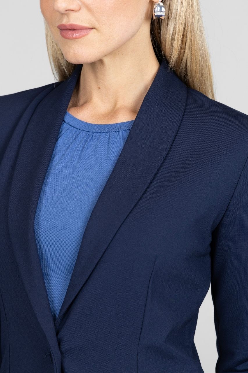 Close up of woman wearing navy blazer with a plain background