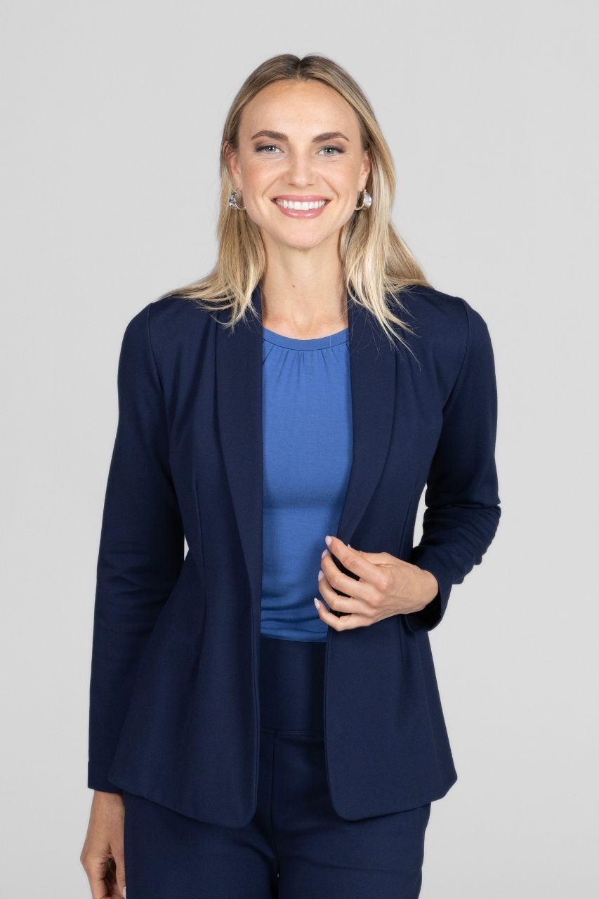 Woman wearing a navy blue blazer with matching high waisted pants over a white background