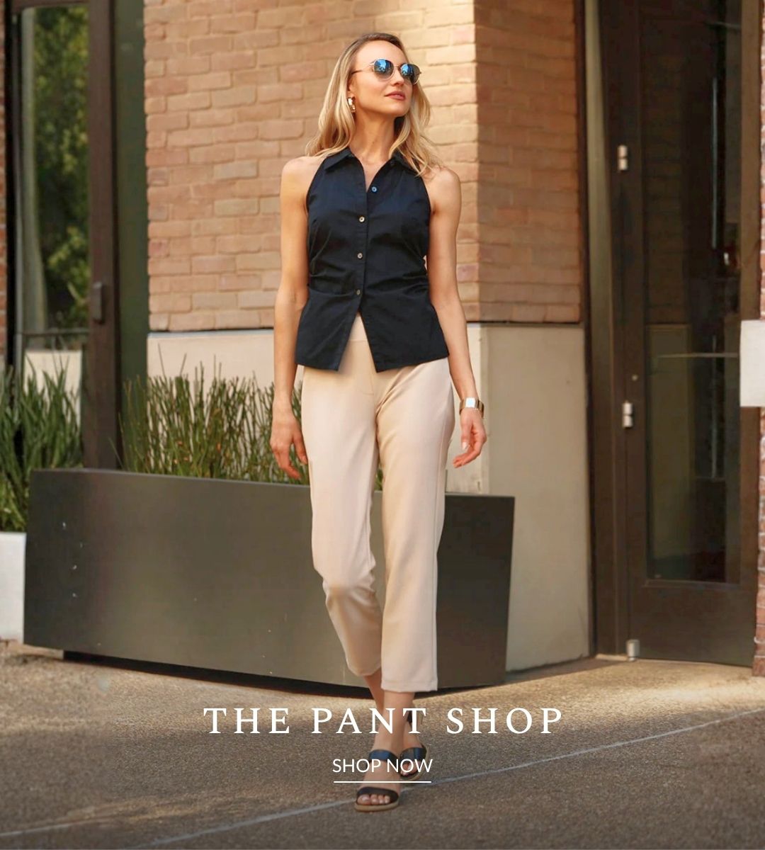 Woman walking on the sidewalk wearing beige ankle pants and black sleeveless button up