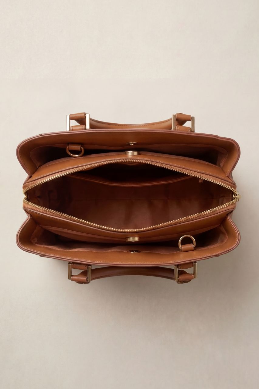 Inside view of a brown PU leather hand bag on a beige background