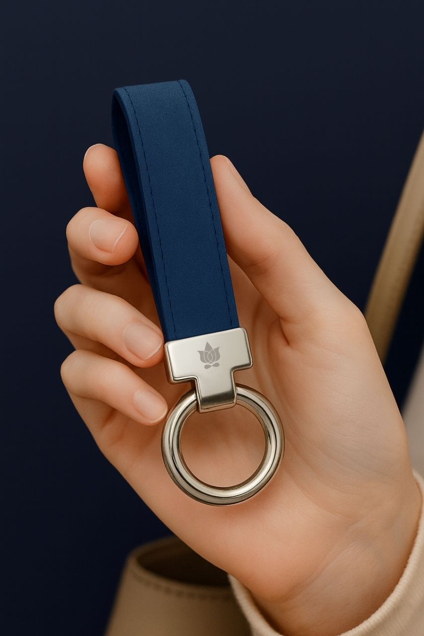 Hand holding a blue keychain with a silver ring against a dark background