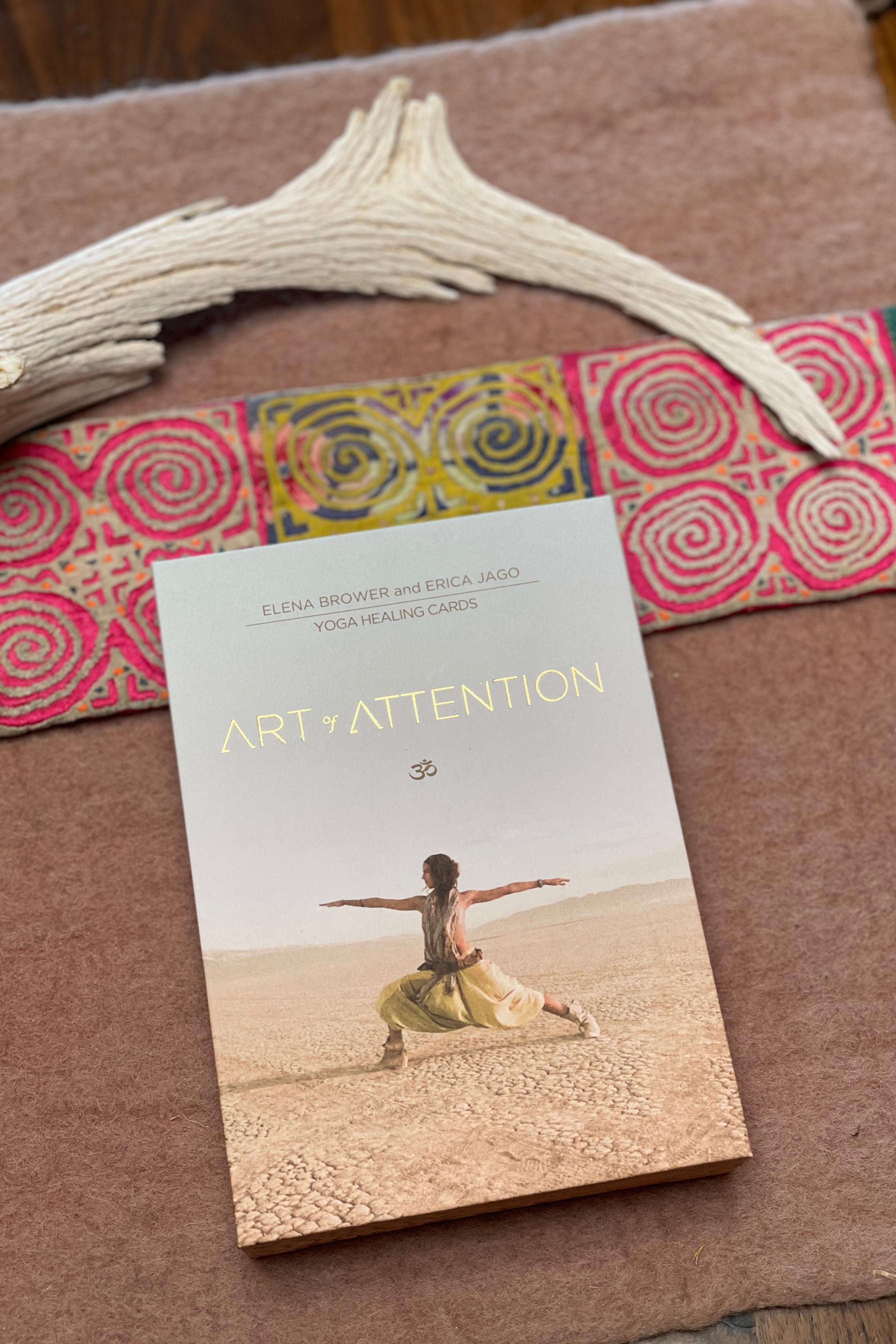 Book titled 'Art of Attention' by Elena Brower and Angela Judd on a textured surface with decorative elements.