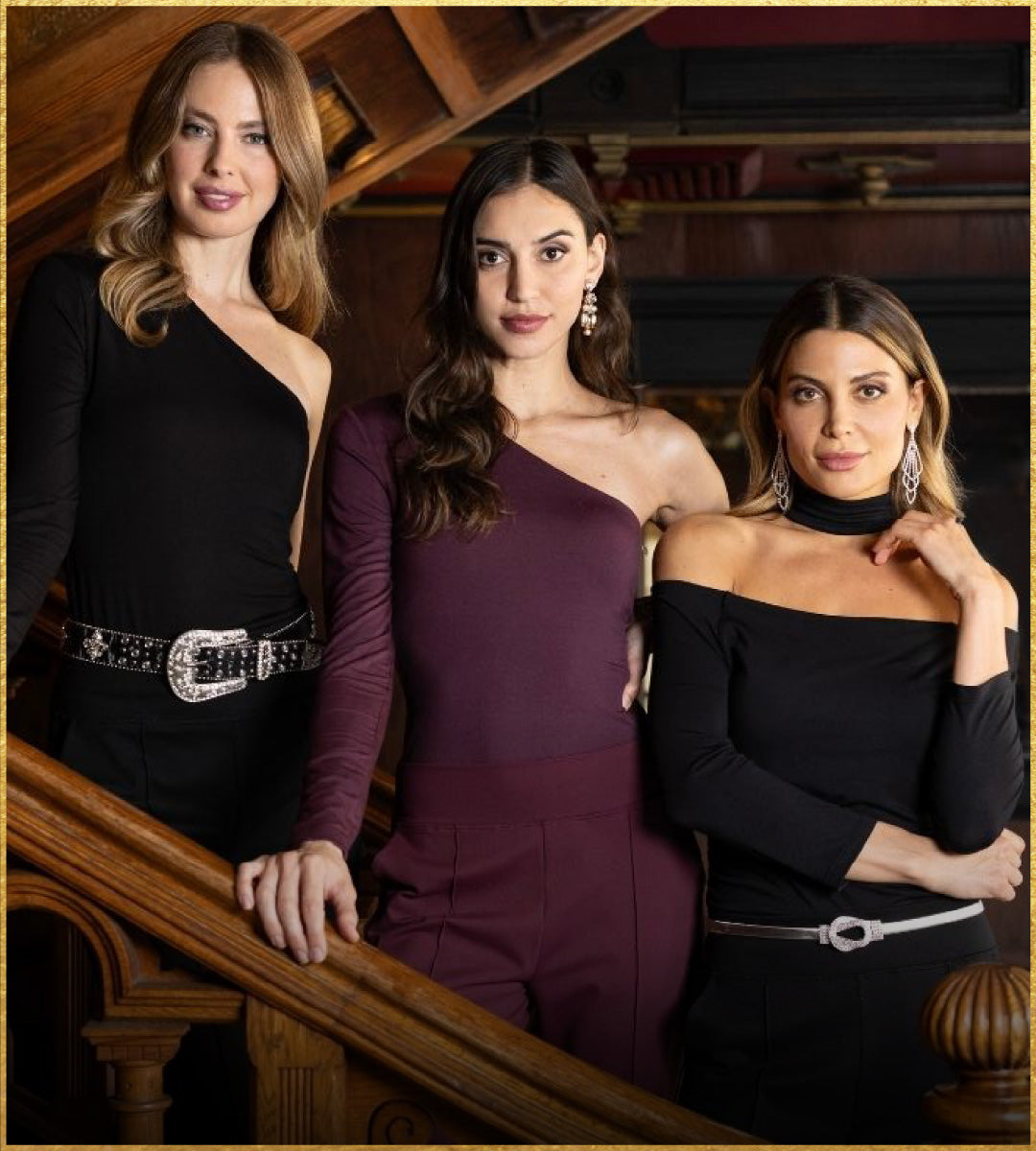 Three women posing together on a staircase in formal attire.