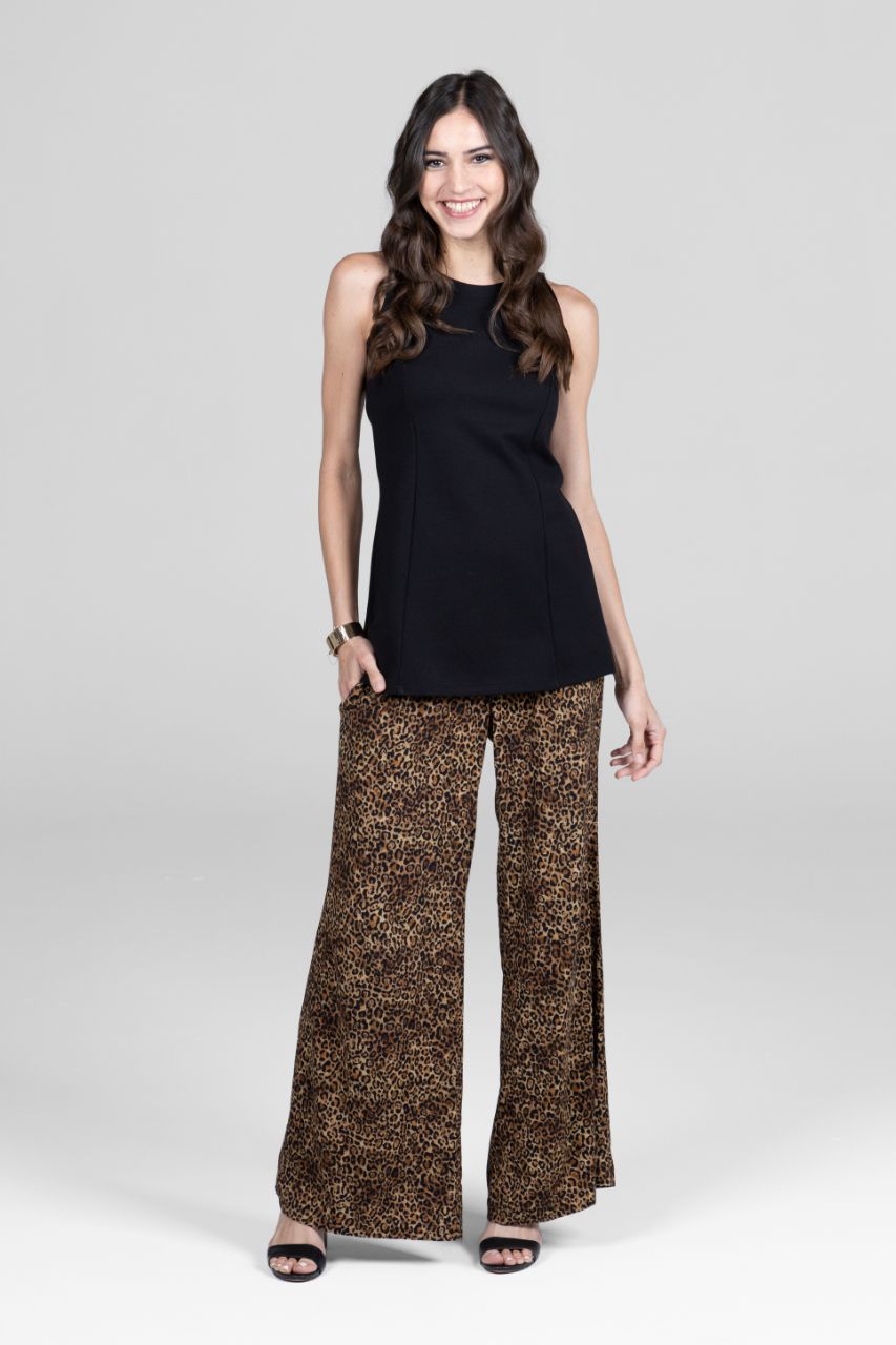 Woman wearing a black sleeveless top and leopard print pants on a white background