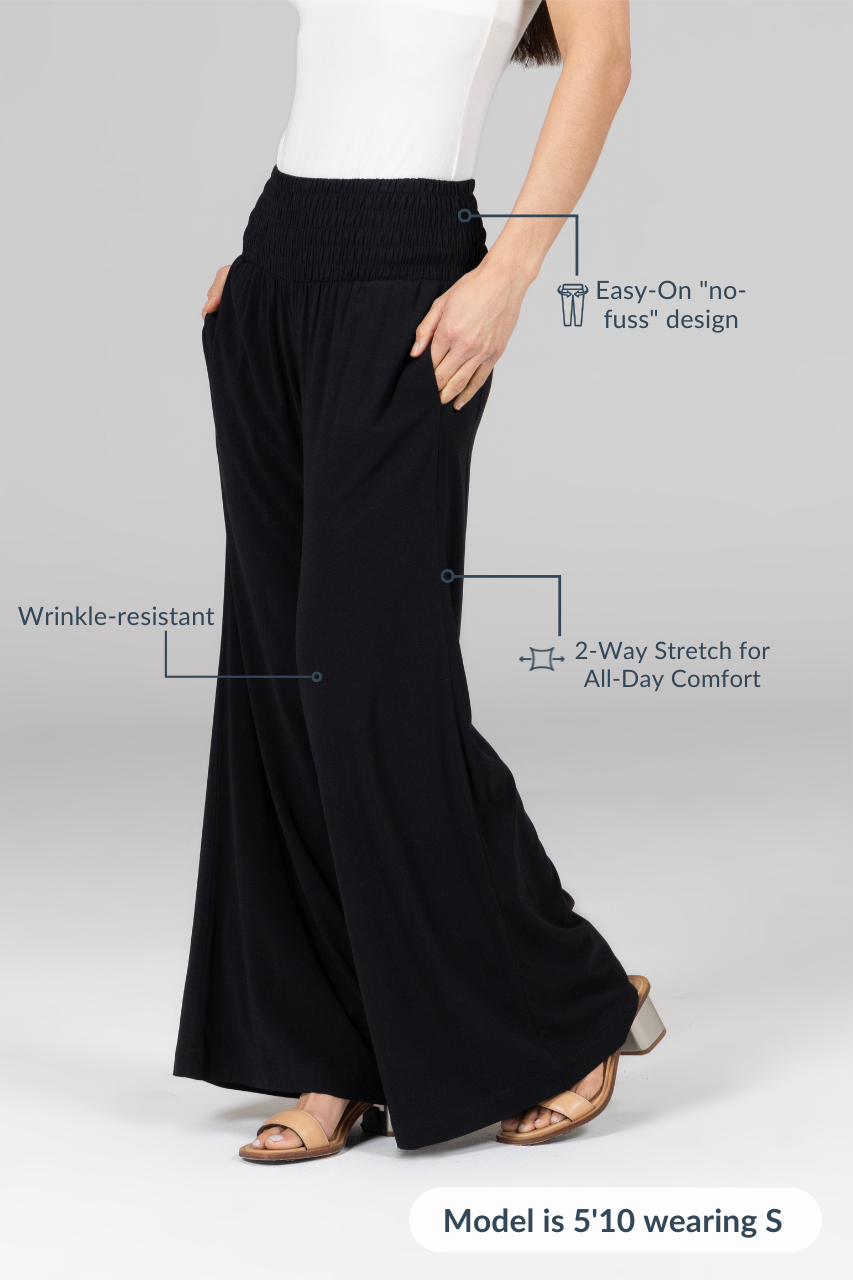 Woman showing the side of black high waisted wide leg pants with attributes: Easy-on "no-fuss" design, Wrinkle-resistant, 2-way stretch