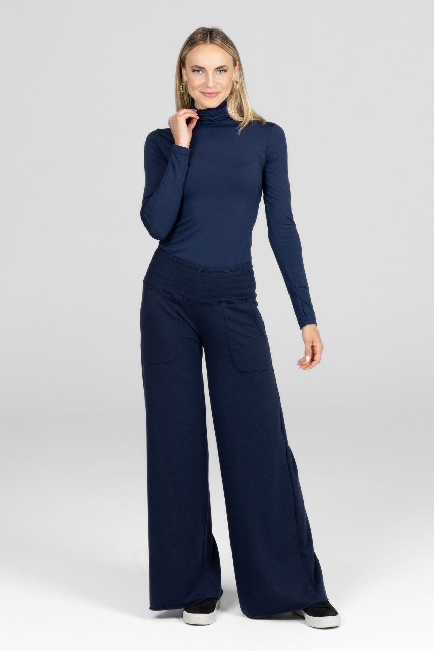 Woman wearing a navy blue outfit with a turtleneck top and wide-leg pants on a white background