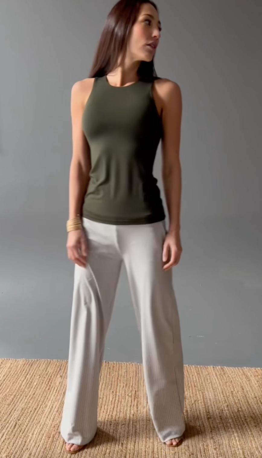 Woman posing wearing a green tank top and striped wide leg pants