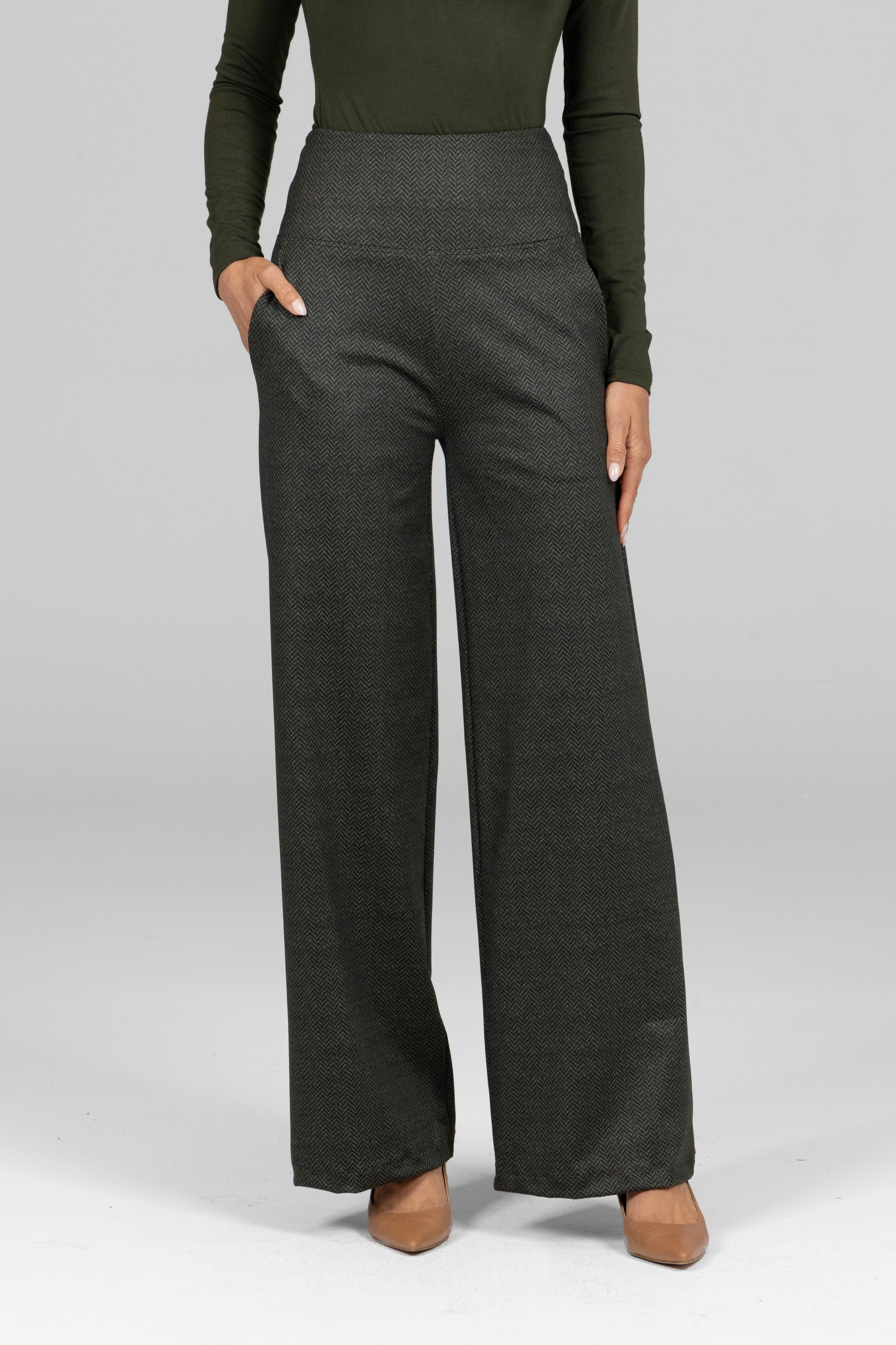 Person wearing dark gray wide-leg pants with a green long-sleeve top on a light gray background