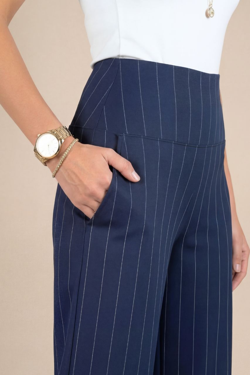 Navy pinstripe pants worn by a person on a beige background