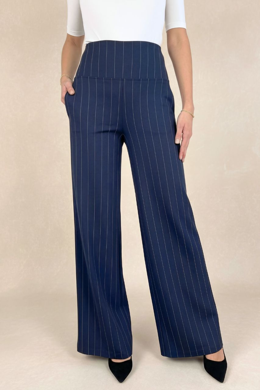 Navy pinstripe pants worn by a person on a beige background