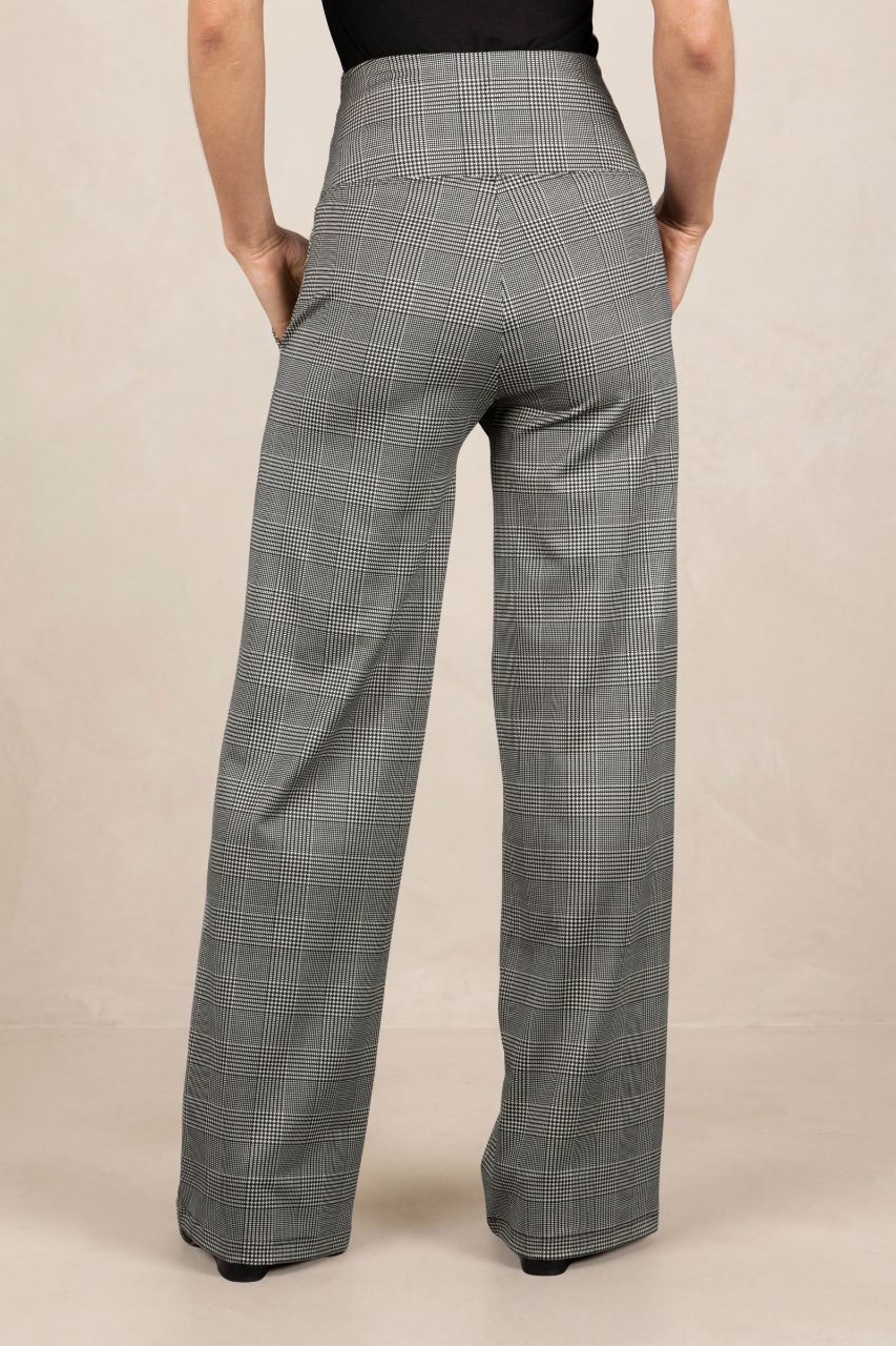 Person wearing black plaid pants on a beige background