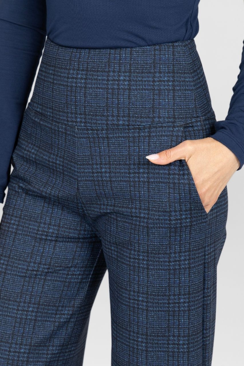 Close up of woman wearing navy plaid pants worn by a person on a white background