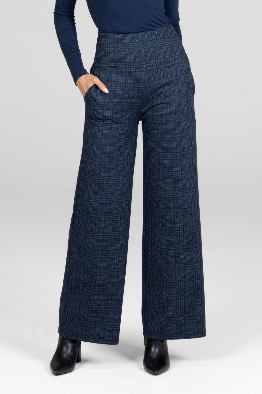Woman wearing navy plaid pants worn with a navy long sleeve top on a white background