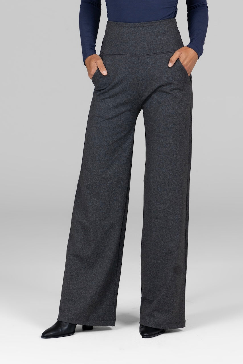 A model wearing high-waisted wide-leg pants in charcoal grey color, with hands in front pockets