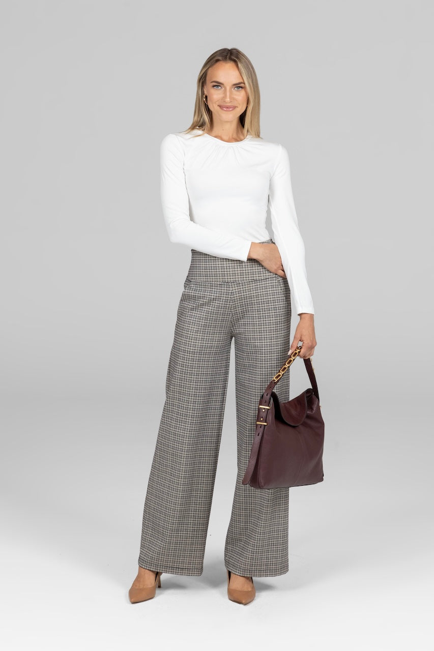 Woman wearing white long sleeve top with high waist wide leg pant with grey tattersall print