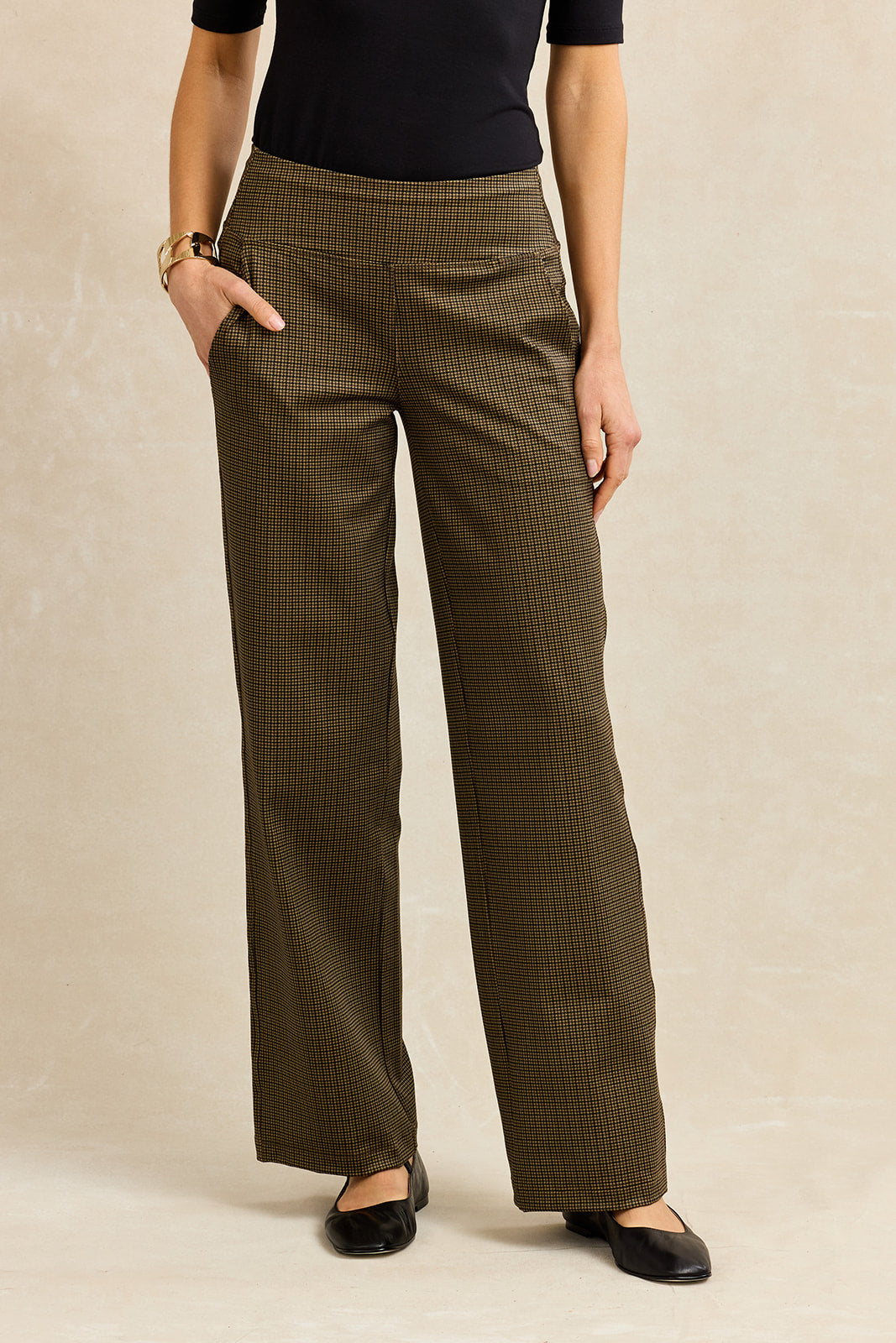 Person wearing brown houndstooth pants on a beige background