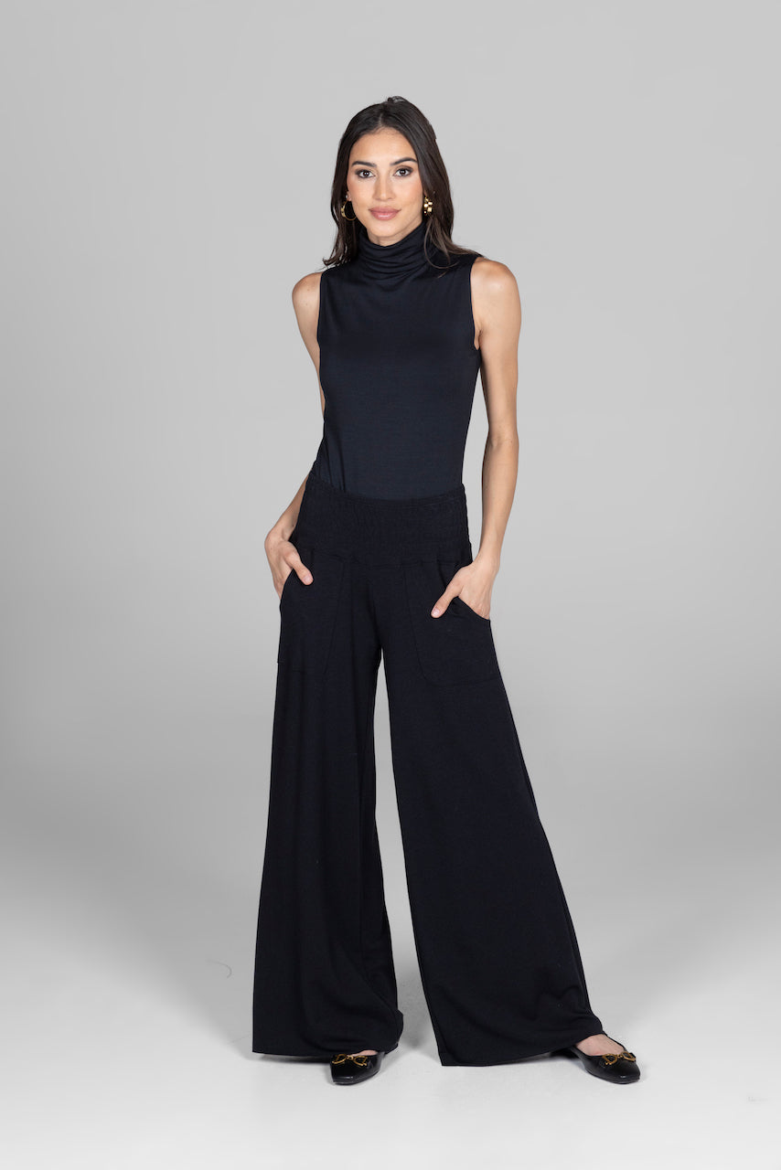 Front view of a model wearing the Sleeveless Turtleneck in black, paired with boho pants, highlighting a relaxed and stylish combination