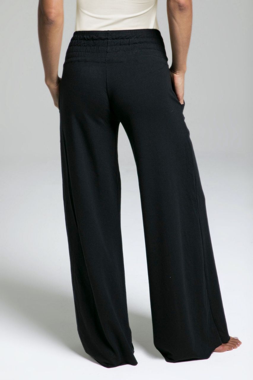 Back view of black wide-leg lounge pants worn by a woman on a plain background