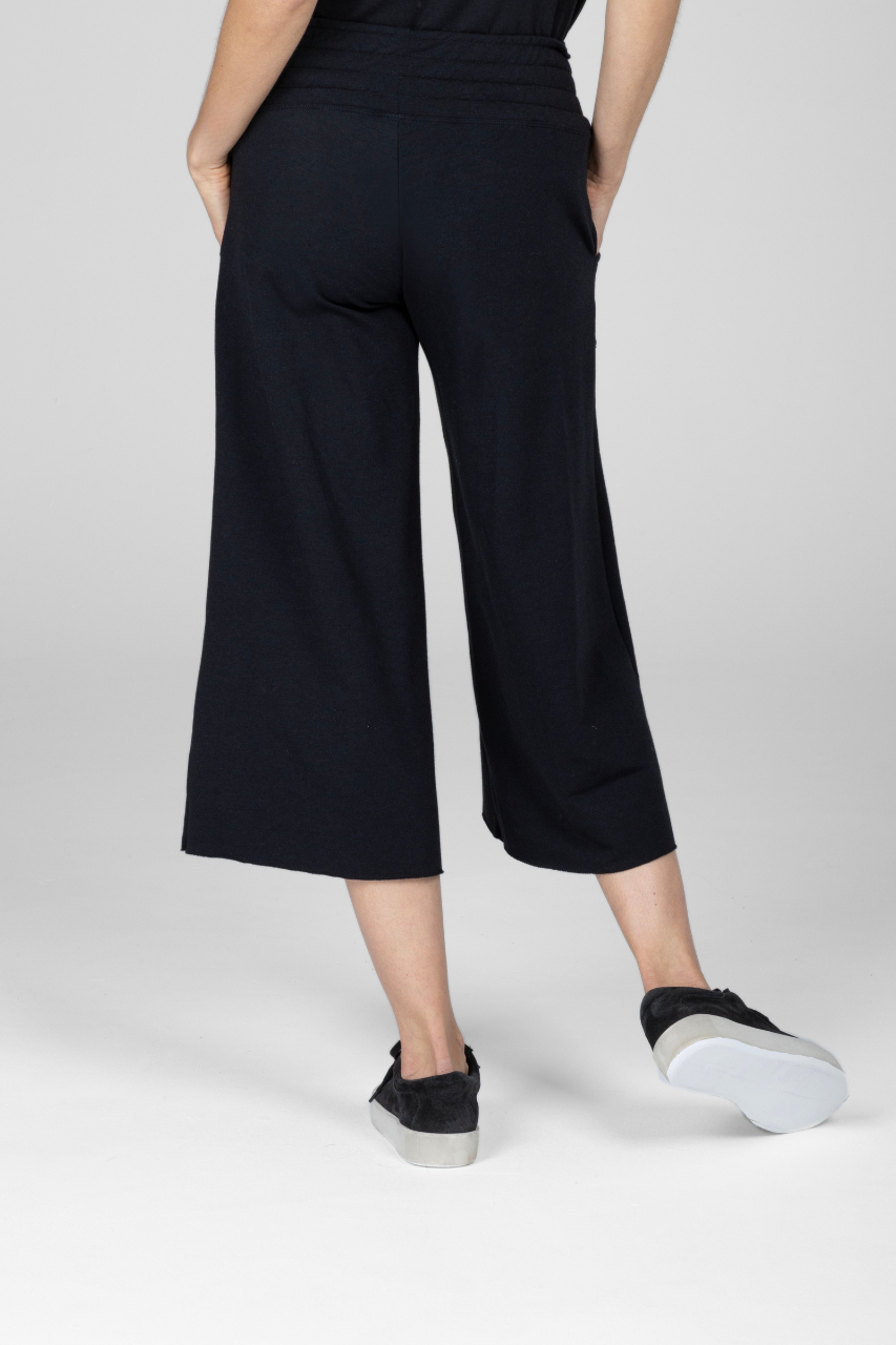 Back view of woman wearing black cropped lounge pants with smocked waistband