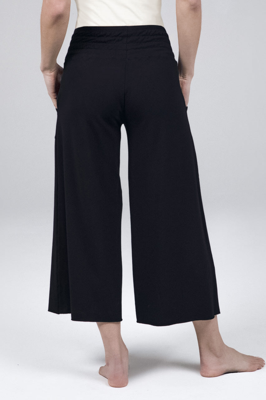 Back view of woman wearing black cropped lounge pants with smocked waistband