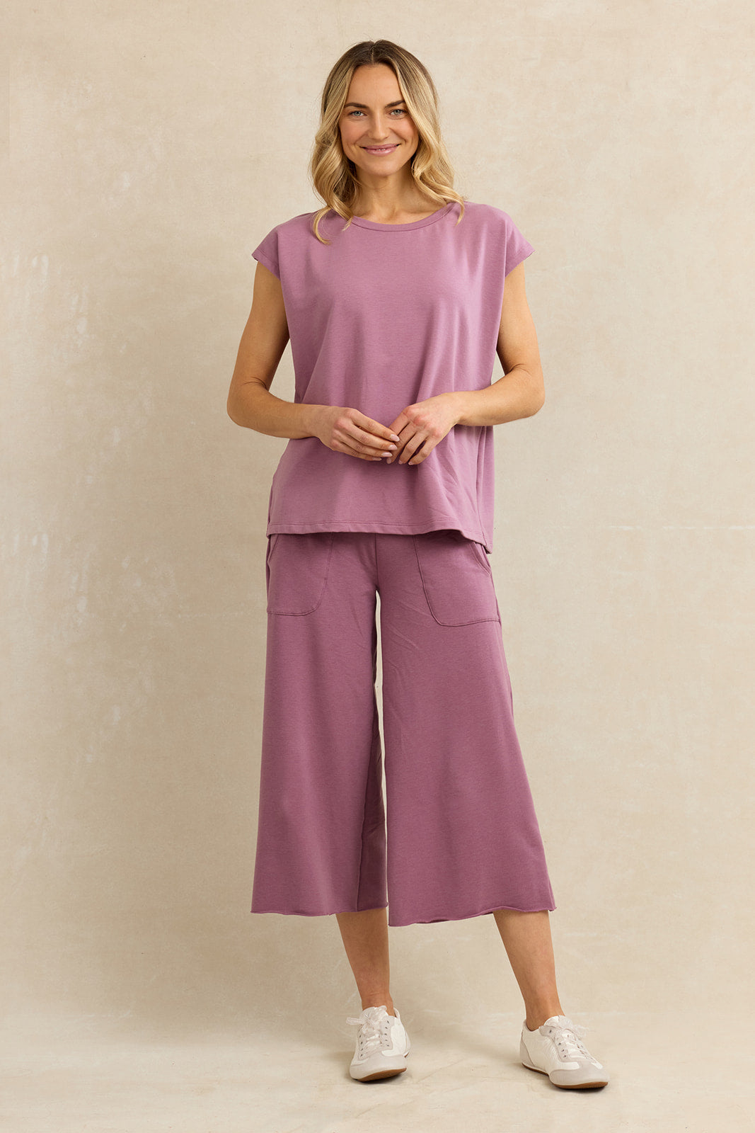 Full length image of a woman wearing a matching pink lounge set with cropped pants