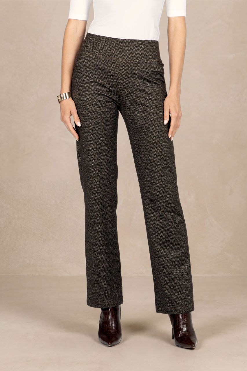 Person wearing brown herringbone pants and a white short sleeve top on a beige background