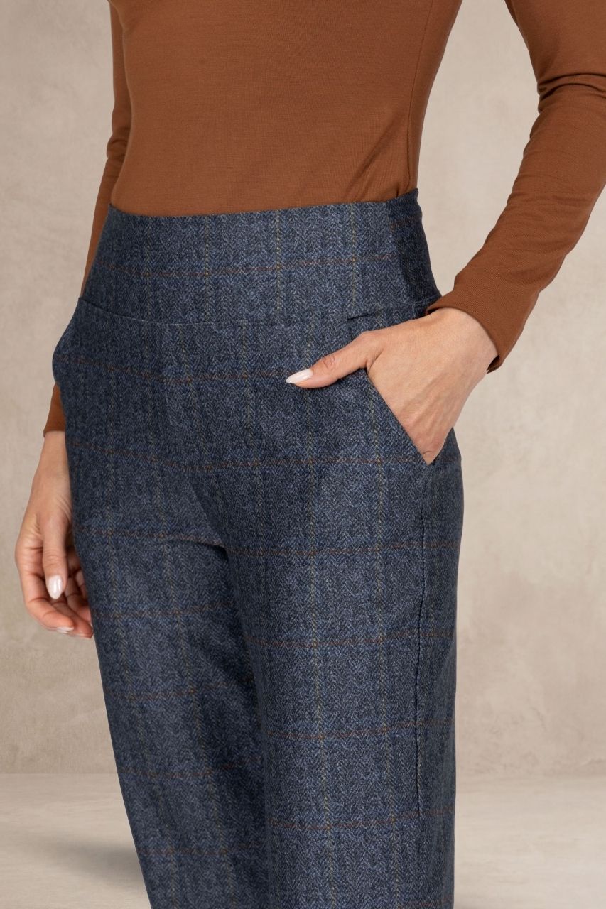 Close up view of grey tartan pants on a beige background