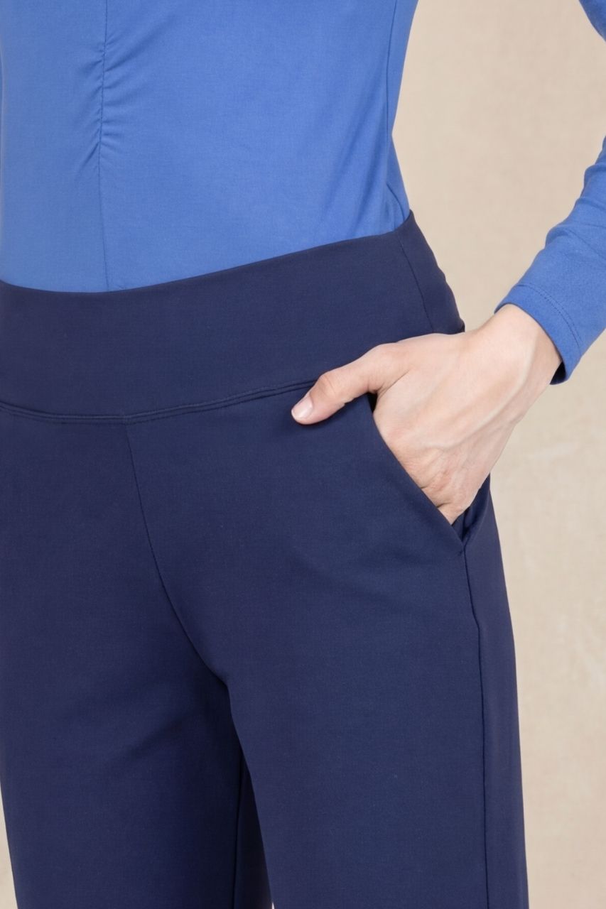 Close up view of a navy blue pant in front of a beige background