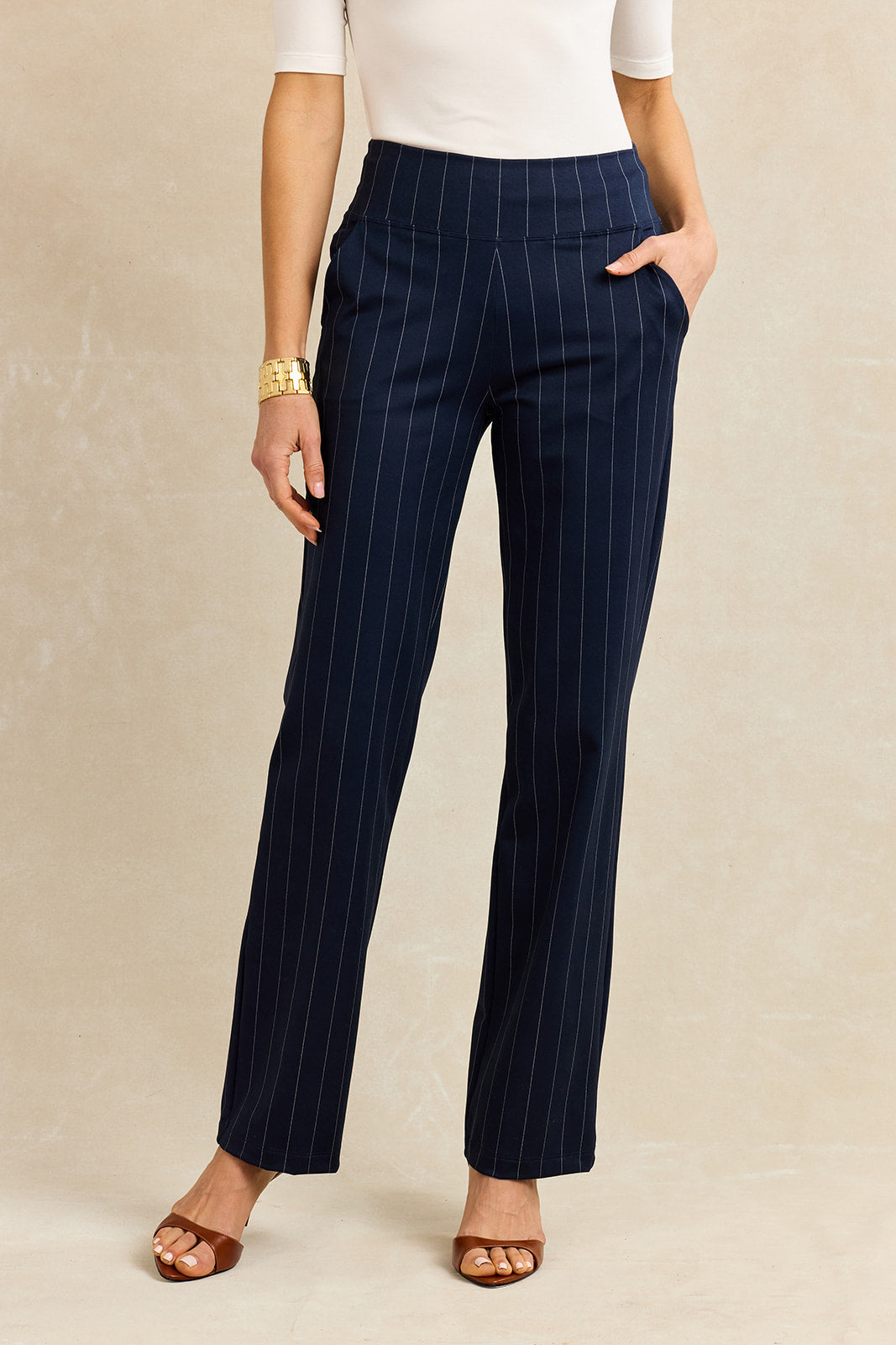Navy pinstripe pants worn by a person on a beige background