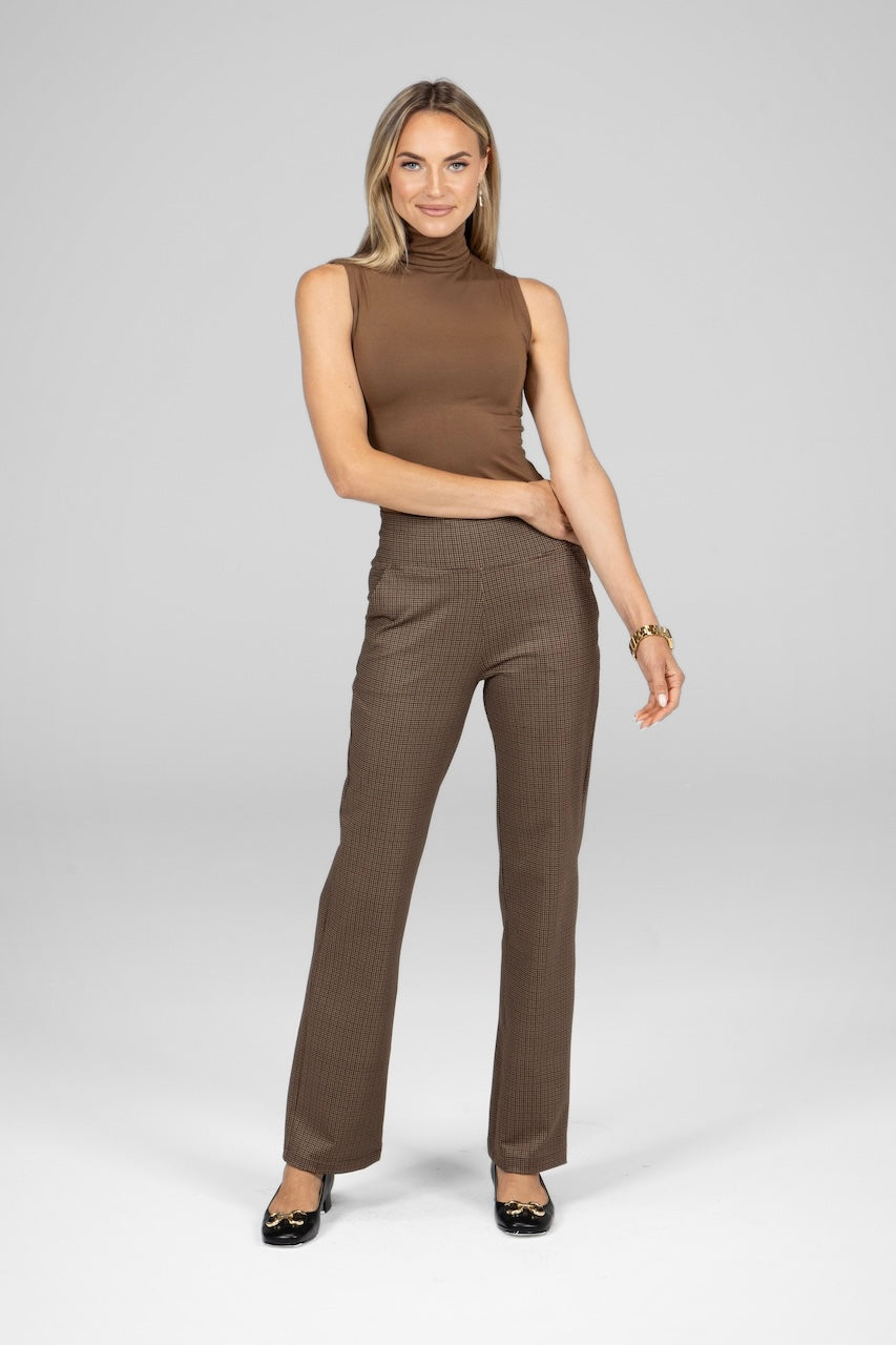 Woman wearing dark khaki sleeveless turtlenecks paired with patterned brown pants