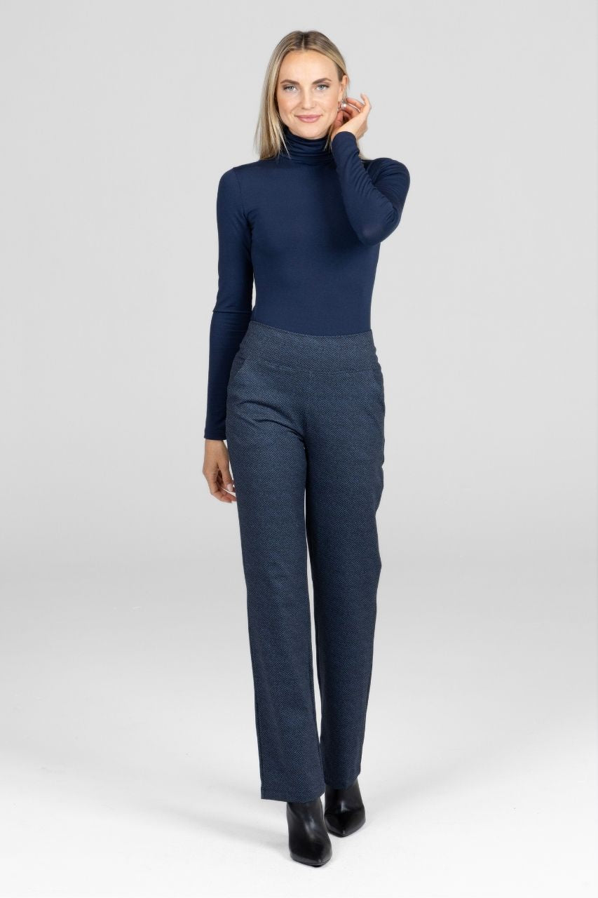 Woman wearing a navy turtleneck and navy tweed pants on a white background