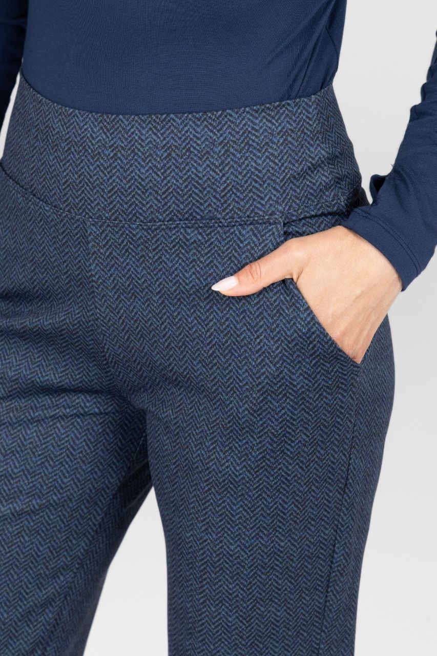Woman wearing navy tweed pants with a plain background