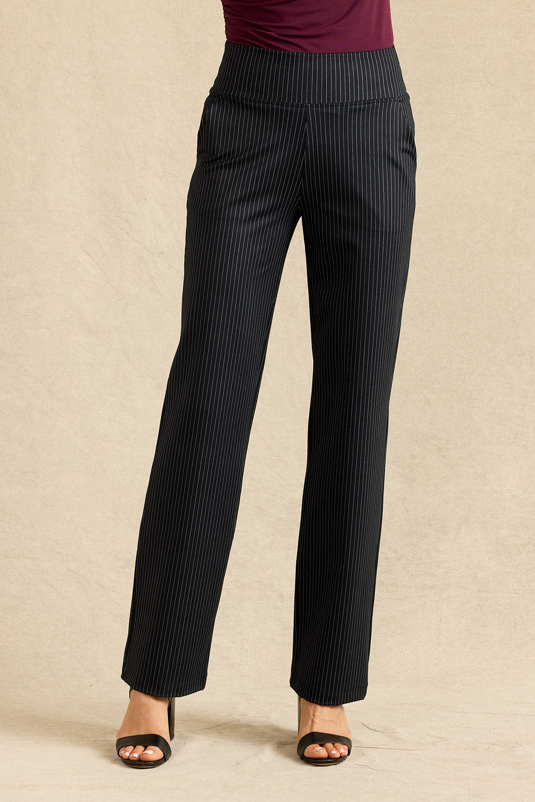 Black pinstriped wide-leg trousers shown on a model from the waist down, paired with a dark burgundy top and black heeled sandals, against a neutral beige backdrop.