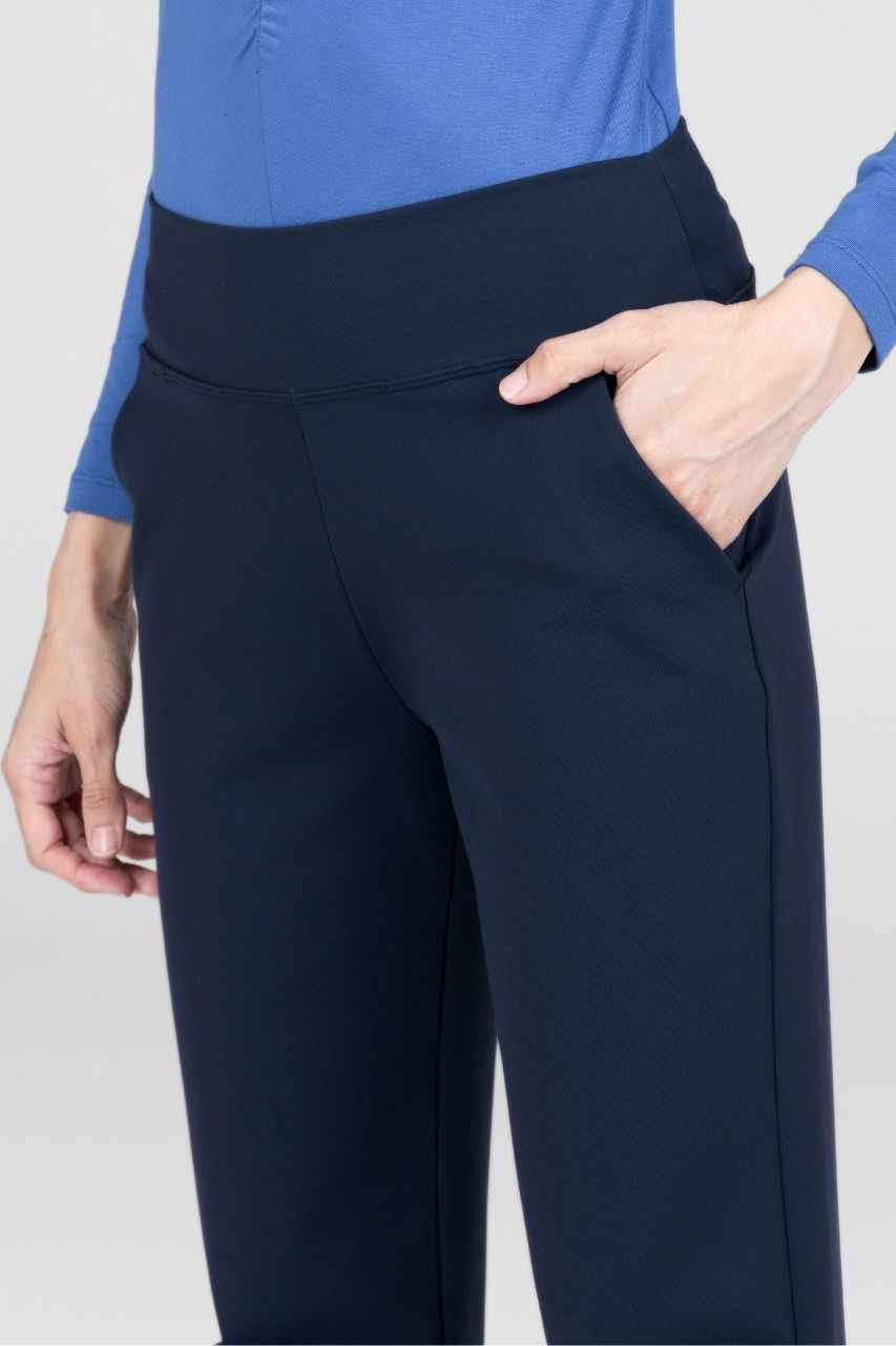 Close up view of woman wearing navy pants worn with a blue top on a light gray background