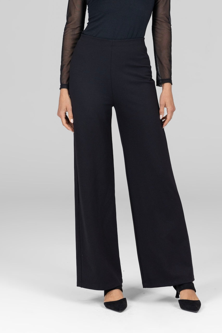 A model waist down wearing black wide leg high-waisted wide leg pants with a black mesh long sleeve