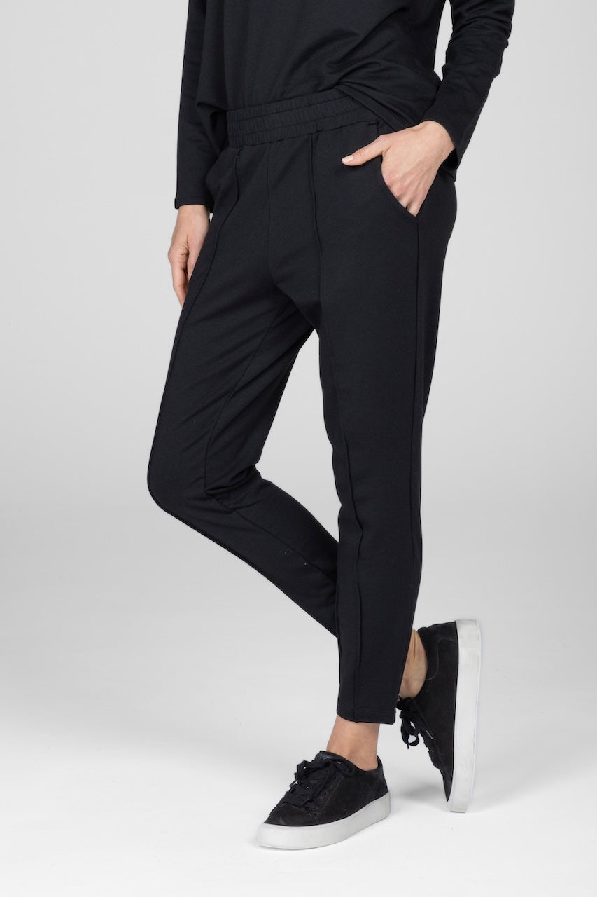 A person wearing black pintuck joggers and a matching top, standing against a plain background.