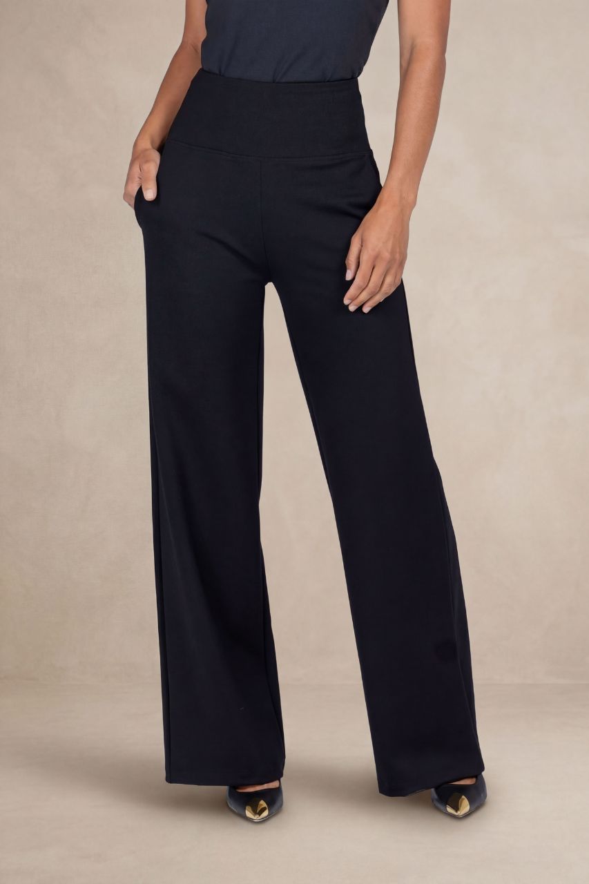 Woman wearing black high waist wide leg pants against a beige background