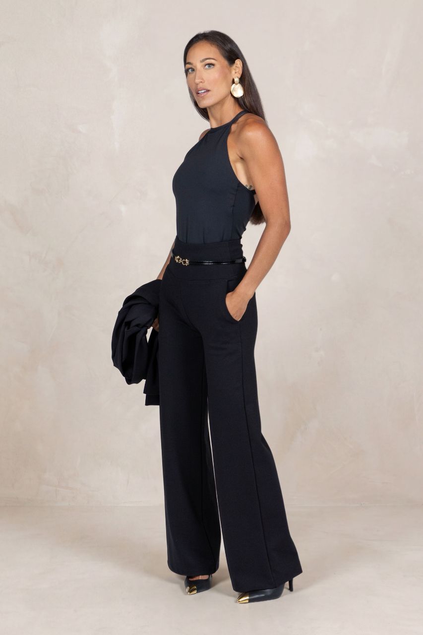 Woman wearing a black outfit with wide-leg pants on a plain background