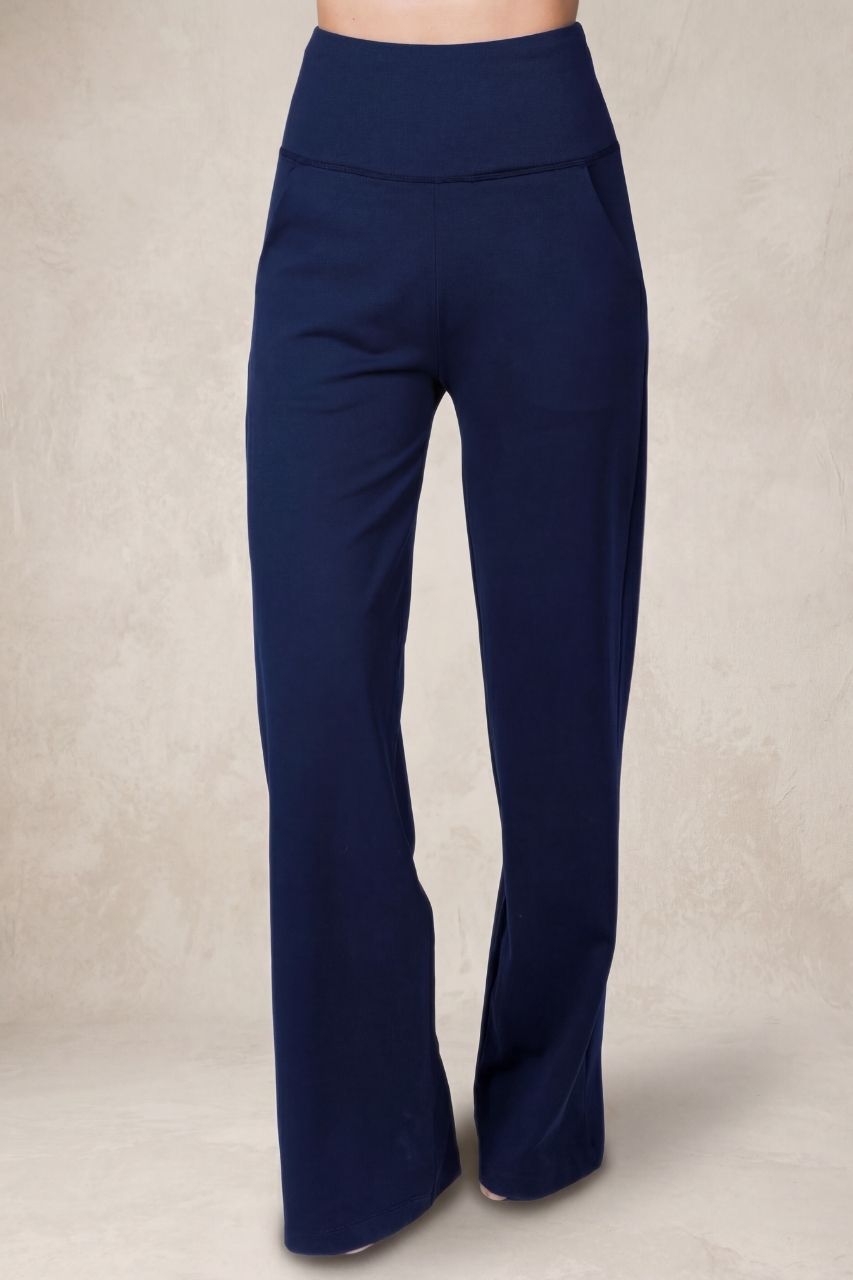 Front view of a woman wearing navy blue high waist wide leg pants in front of a beige background