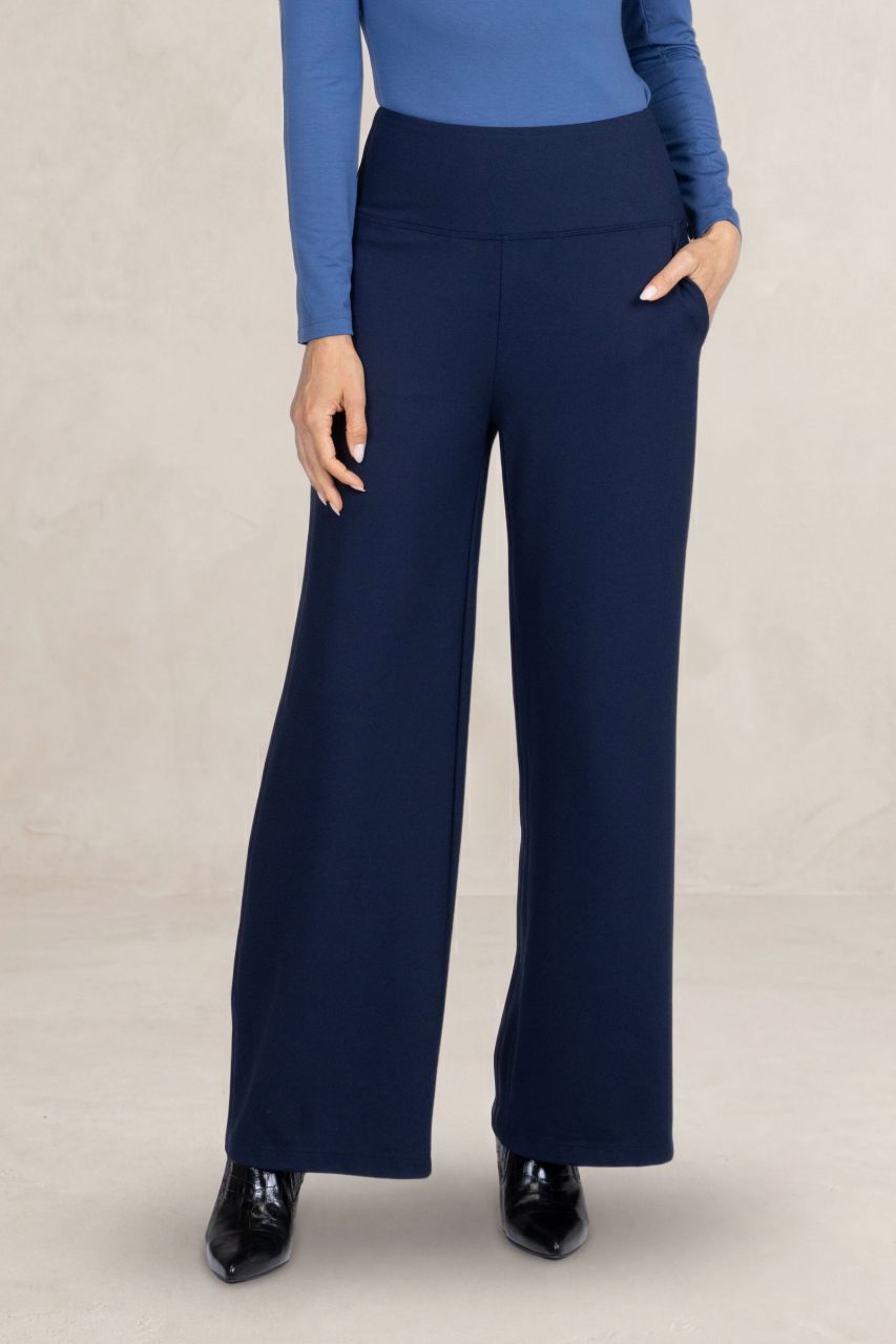 Navy blue wide-leg pants worn with a blue top on a beige background