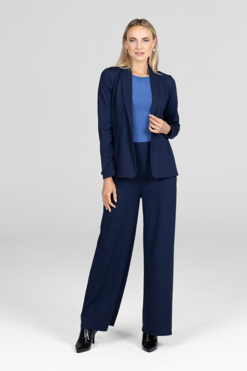 Woman wearing a navy blue blazer with matching navy high waist wide leg pants with a white background