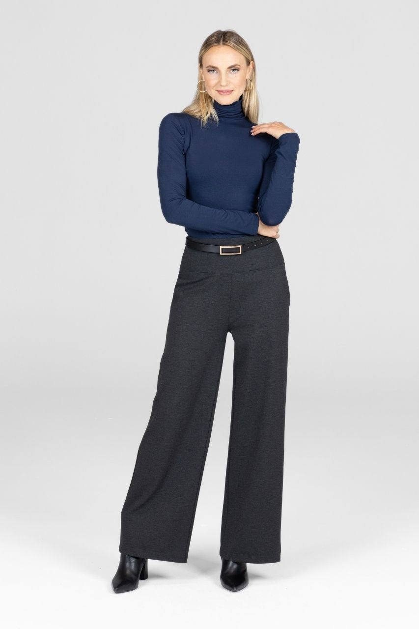 Woman wearing navy turtleneck and dark grey high waist wide leg pant with a black belt