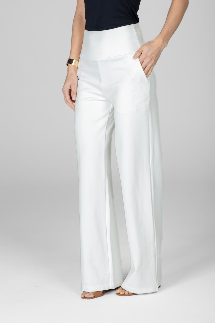 A model wearing high-waisted wide-leg pants in ivory color, paired with a black top and standing against a neutral background.