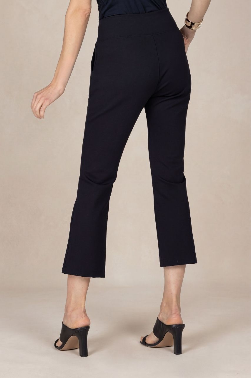 Back view of a person wearing black ankle pants on a beige background