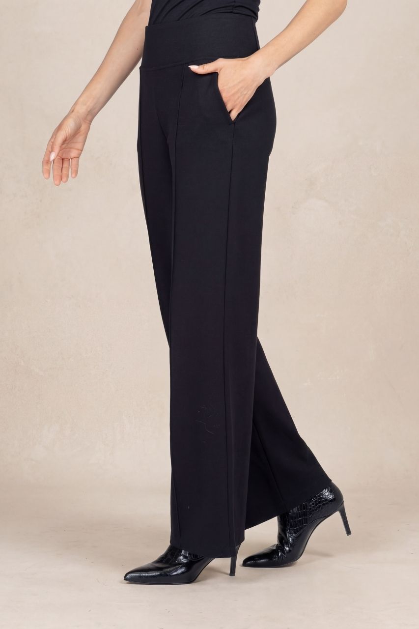 Black pants worn by a person on a beige background