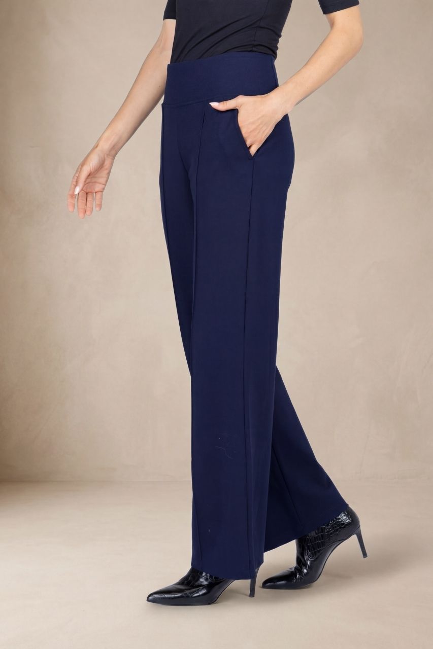 Woman wearing navy blue wide leg pants on a beige background