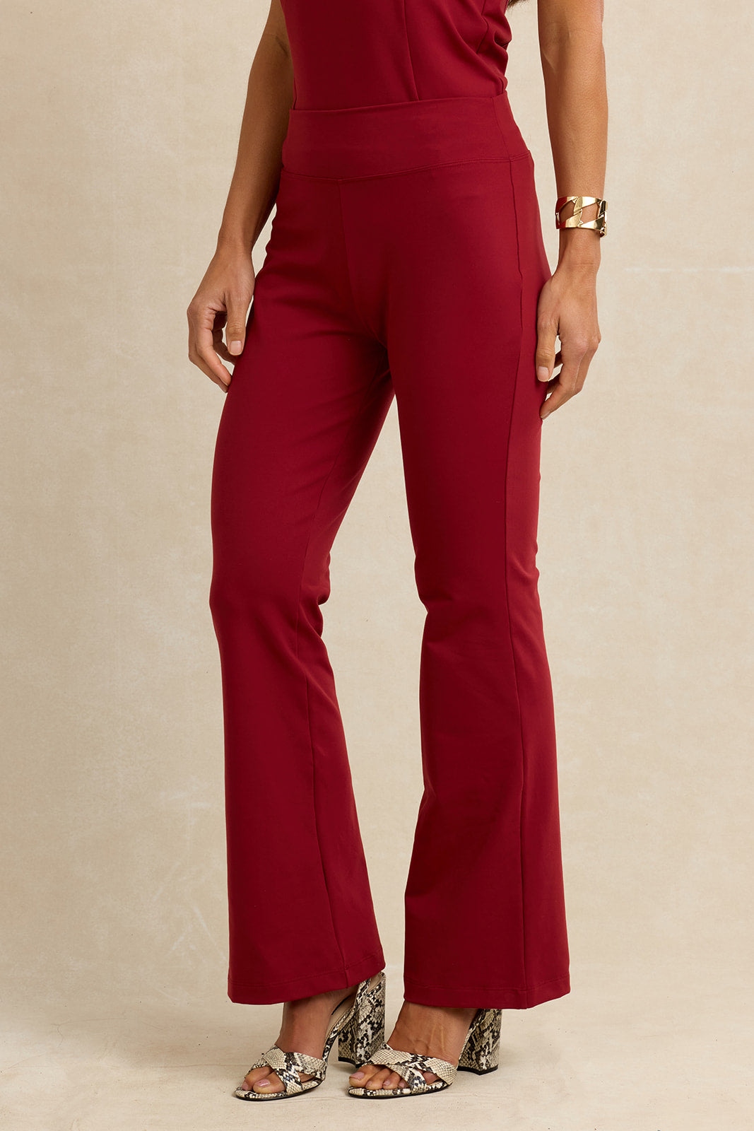 Brick red flared pants worn by a woman on a beige background